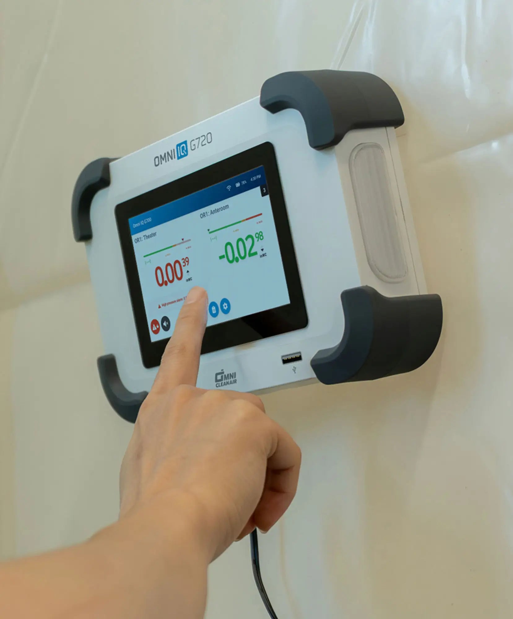 hand interacting with touchscreen on Omni IQ G720 device mounted to white wall